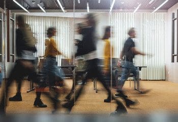 Employees walking through a busy office boardroom