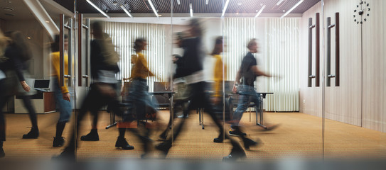 Employees walking through a busy office boardroom