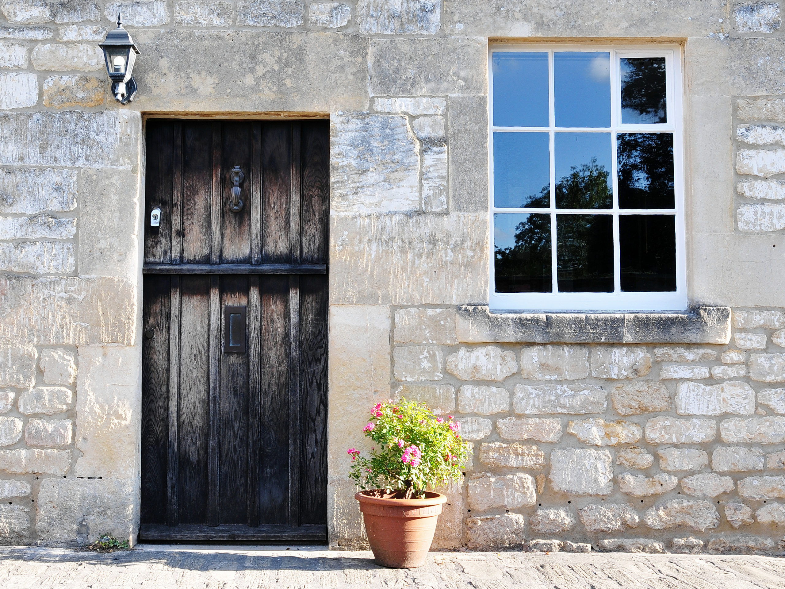 Traditional house with black front door and flowers next to door