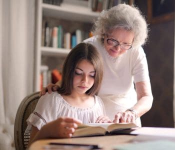 granddaughter reading a book with grandmother