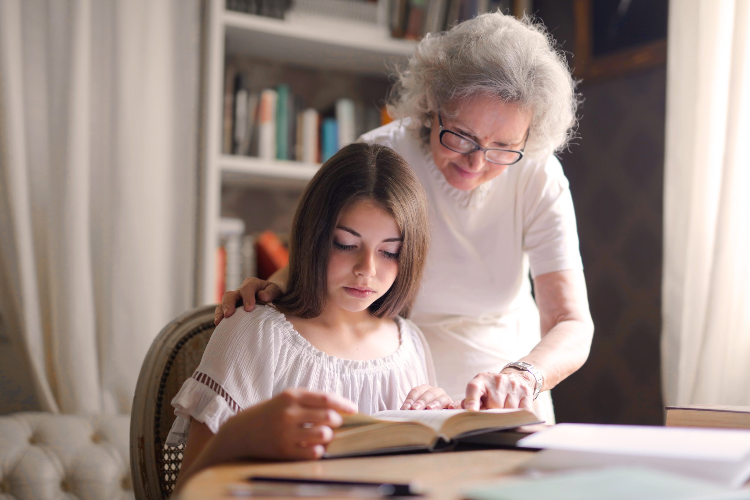 granddaughter reading a book with grandmother