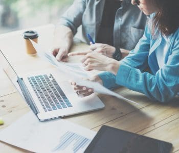 Business people discussing reports with a laptop
